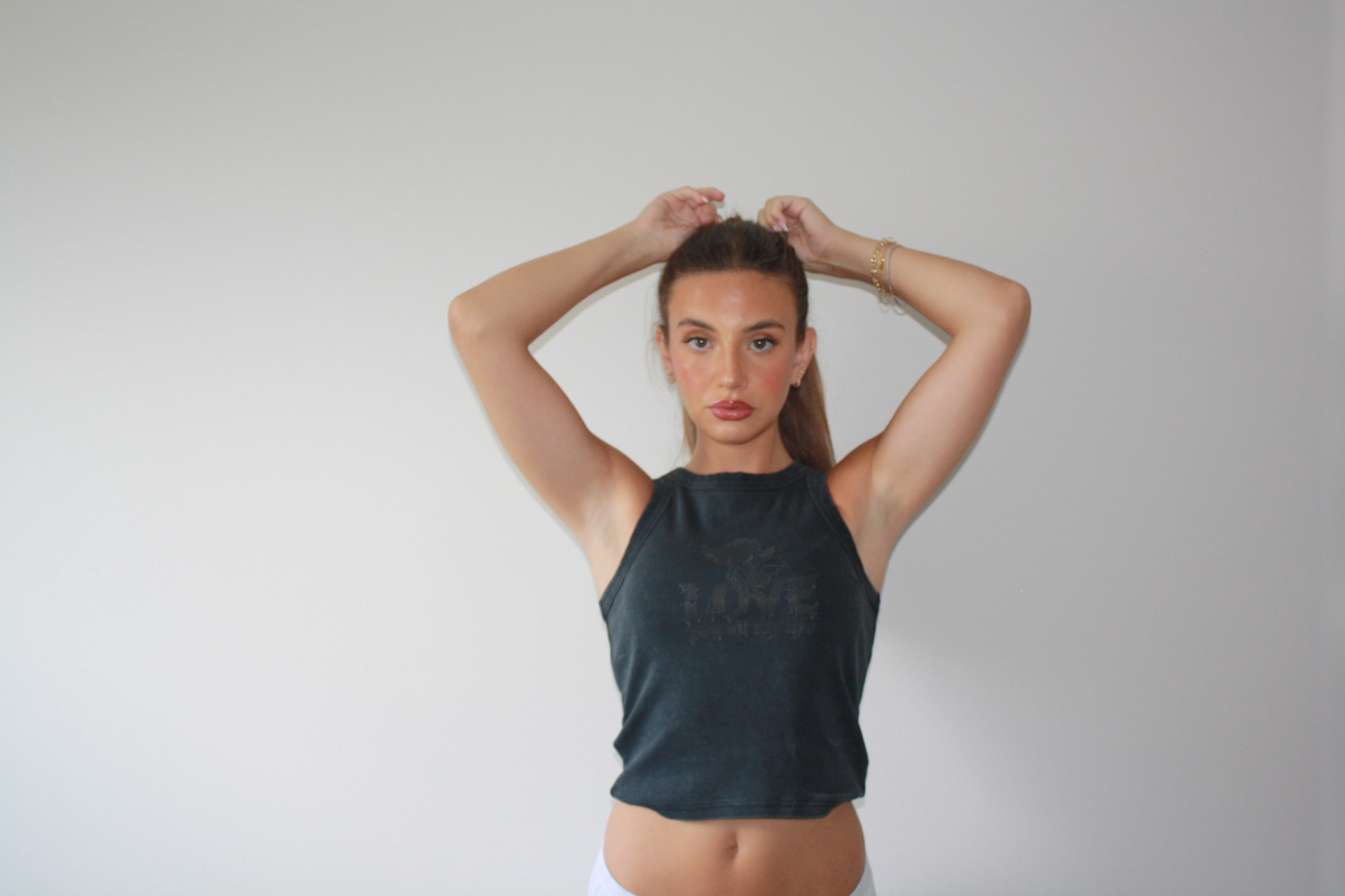 Model wearing a black DMK Studios tank top against a white backdrop